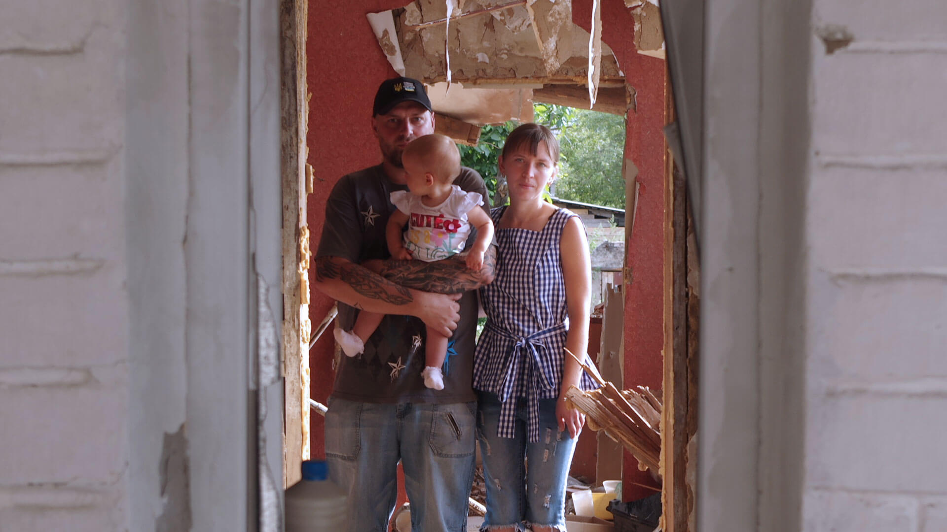 Young family stand in the doorway of their home destroyed in the Ukraine war