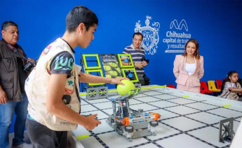 A student is operating a small robot on a large grid-patterned table.